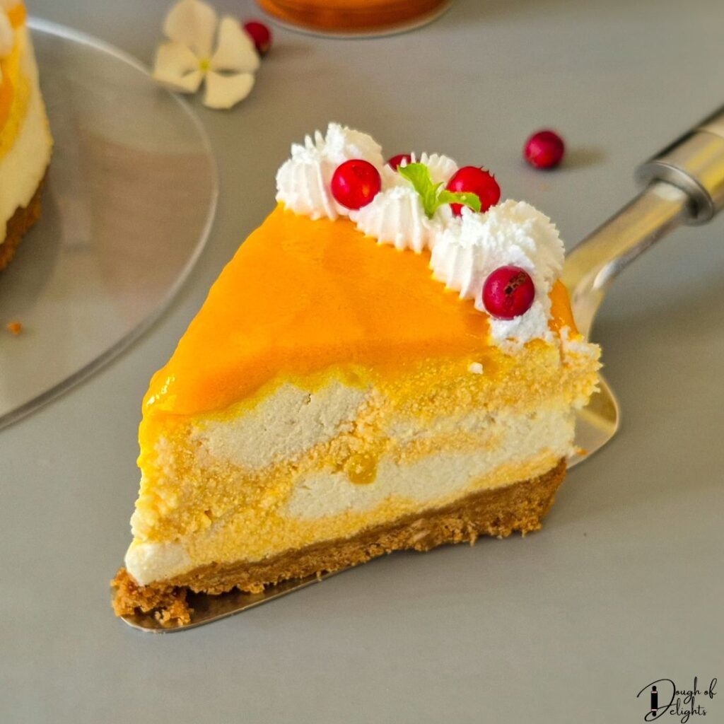 Slice of eggless coconut mango cheesecake with a buttery biscuit base
