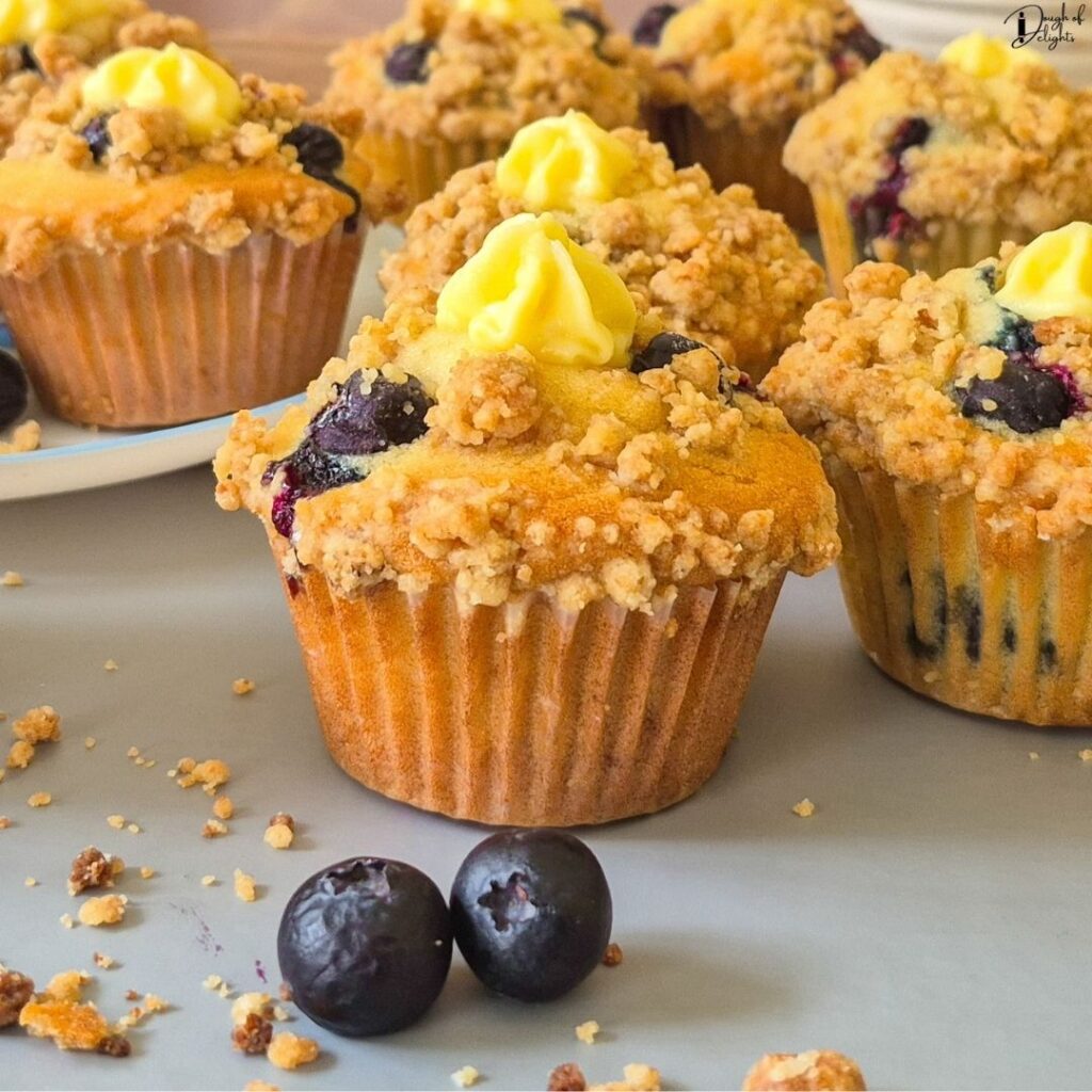 Stack of homemade Blueberry Custard Crumble Muffins showcasing their tall bakery-style tops and buttery crumble.