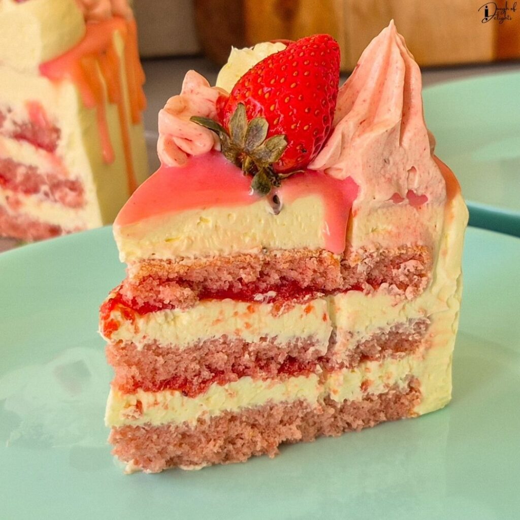 A slice of Strawberry Layer Cake showing three light and fluffy sponge layers with strawberry syrup and Swiss meringue buttercream.