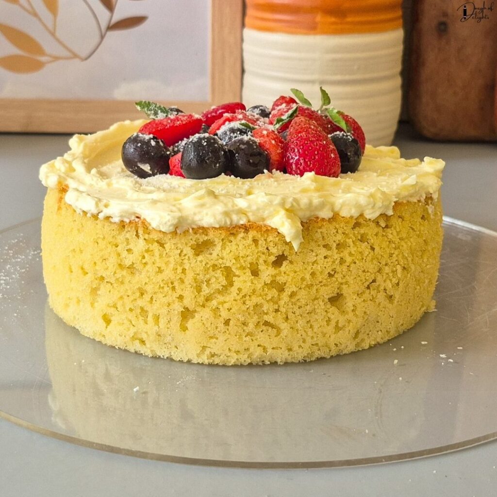 Whole Coconut Sponge Cake frosted with Swiss meringue buttercream and garnished with fresh fruit.