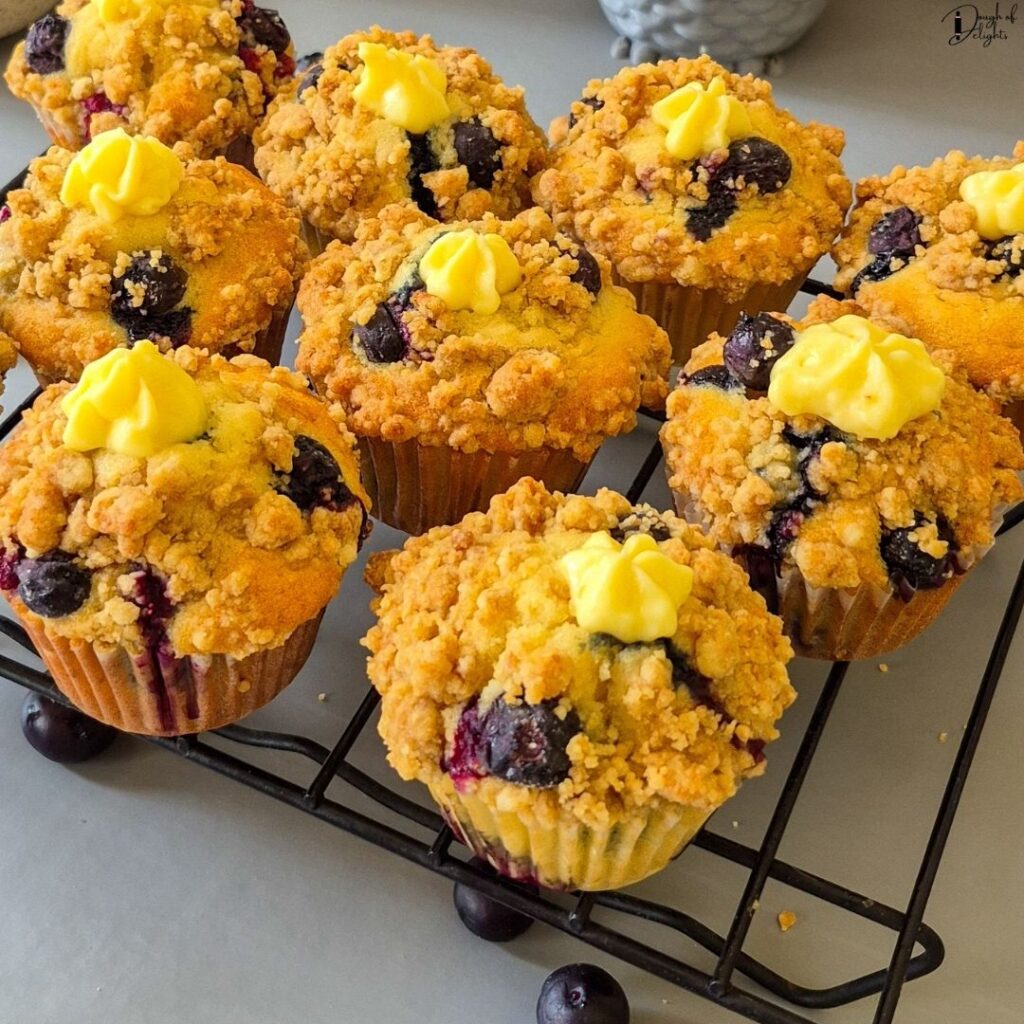 Freshly baked Blueberry Custard Crumble Muffins cooling on a wire rack after baking.